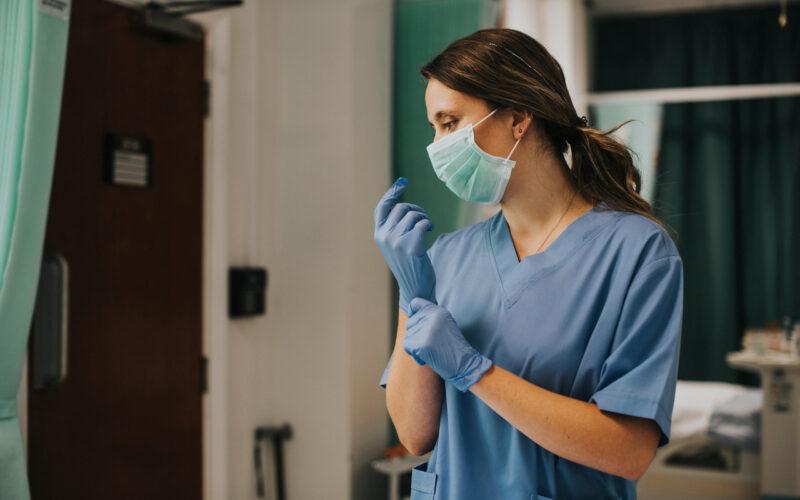 female nurse with mask putting gloves